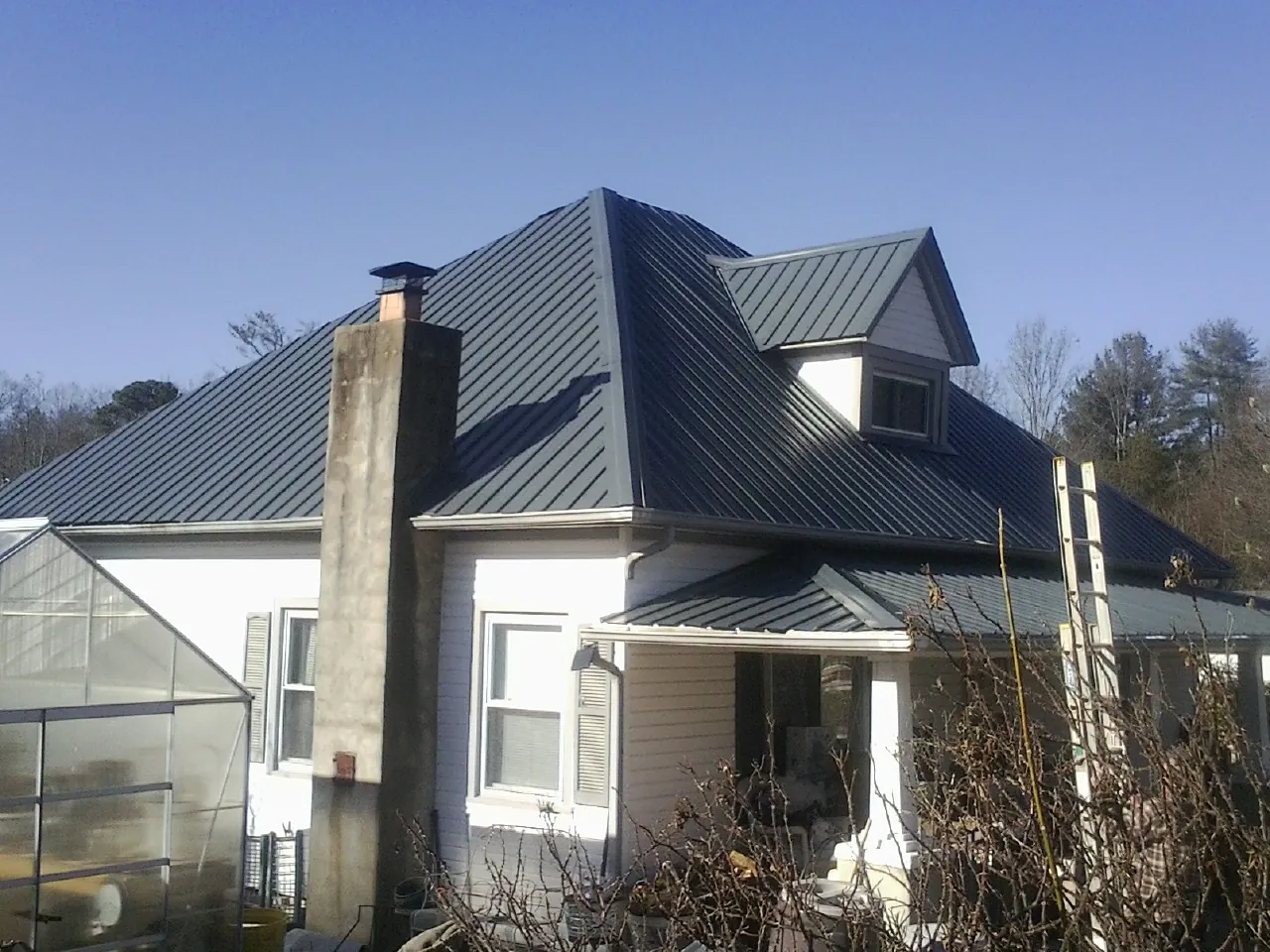 Dark blue standing seam metal roof on a white farmhouse with dormer — Slate & Tile Roof Repair by Roofing Brothers in Granite Bay