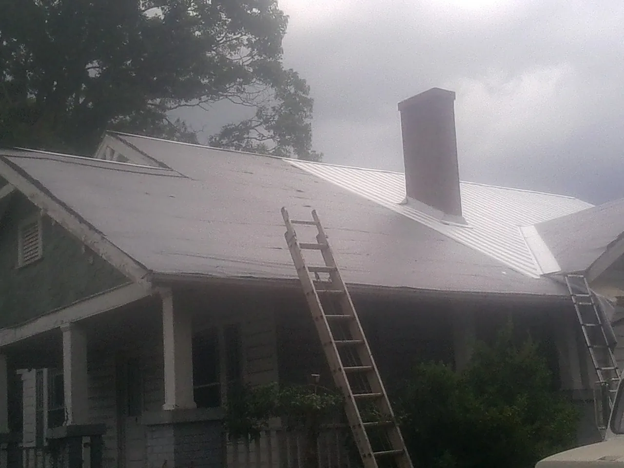 Ladders against a metal roof on an older home with a brick chimney in Granite Bay