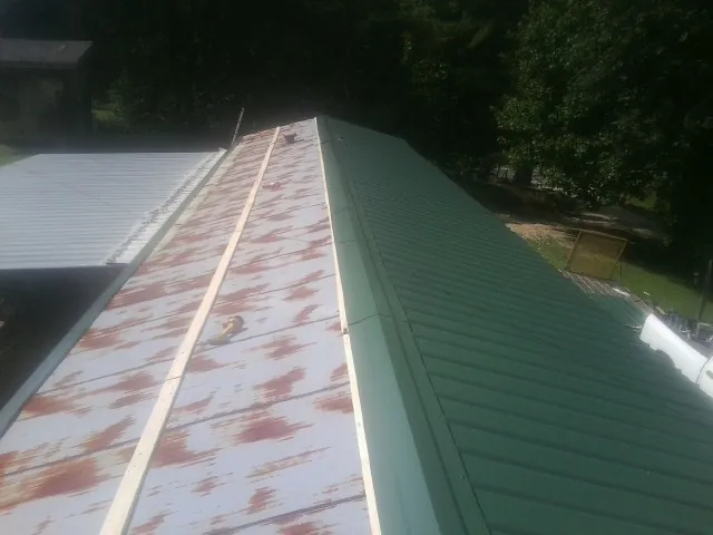 Old rusted panels beside newly installed green metal roofing — Wind Damage Roof Repair by Roofing Brothers in Granite Bay