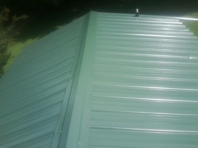 New green metal panels meeting at the ridge of a roof — Flat Roof Repair work by our crew in Granite Bay
