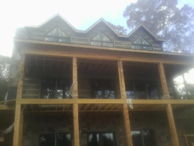 Dormers and porch framing on a large log home under construction — Roof Coating work by our crew in Granite Bay
