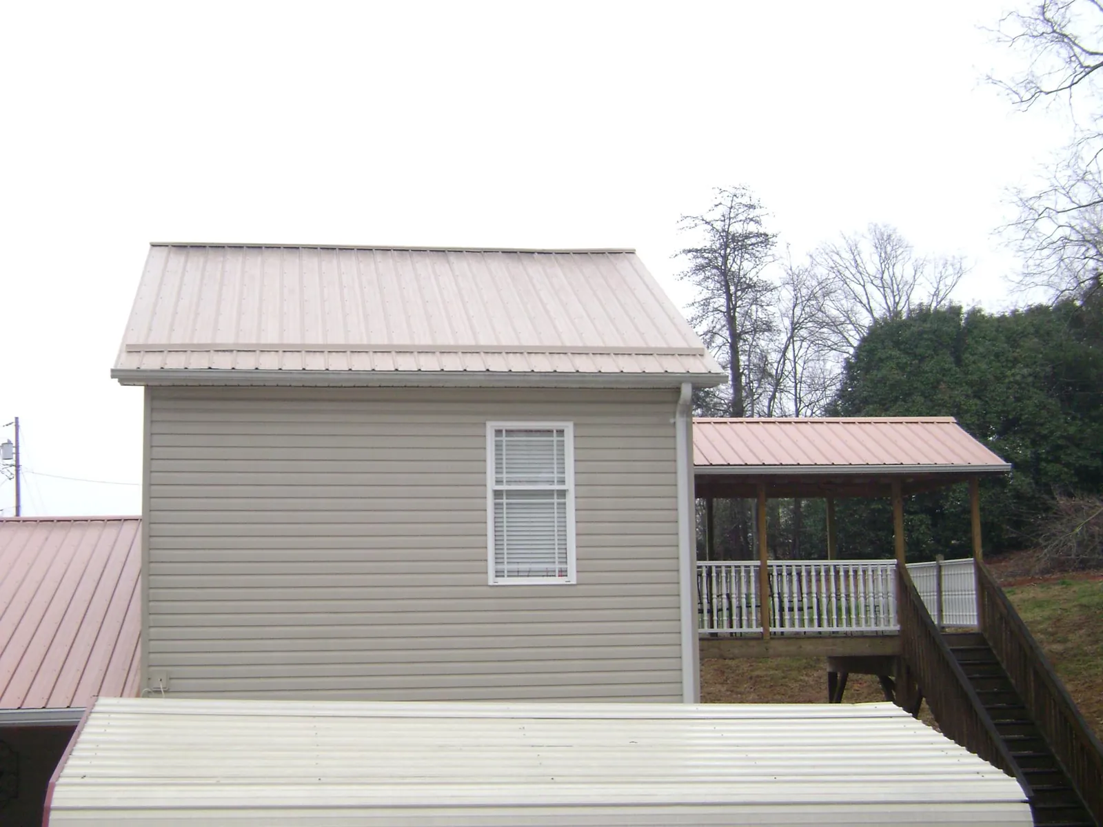 Tan metal roofs on a two story addition and attached porch, from a Roof Replacement job in Granite Bay