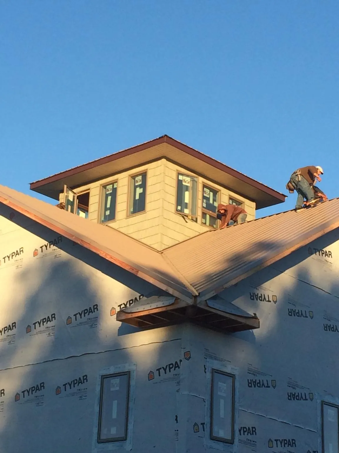 Roofers working around a rooftop cupola on a new metal roof at sunset — Roof Waterproofing in Granite Bay by Roofing Brothers